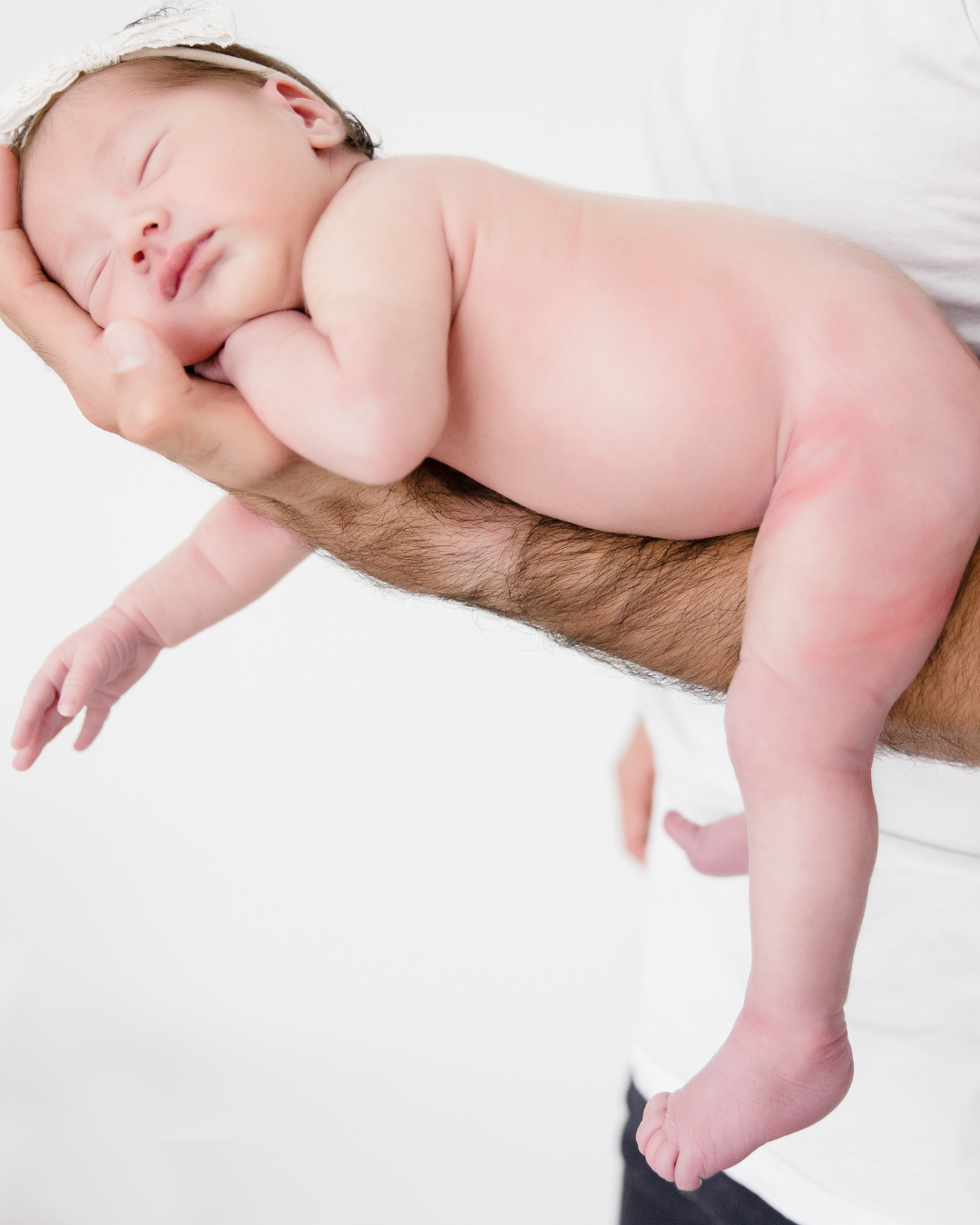 Newborn resting on a parent's arm